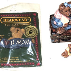 May include: A collection of Boyd's Bears and Friends figurines. Includes a bear pin with "U MOM" banner, a bear figurine, and a bear figurine on a decorative box. The box is brown with gold accents.