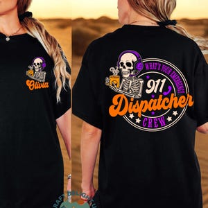 Puede incluir: Camiseta negra con un gráfico de esqueleto con auriculares y una taza de café. La parte delantera de la camiseta tiene el nombre "Olivia" en escritura naranja. La parte trasera de la camiseta muestra el texto "What's Your Emergency 911 Dispatcher Crew."