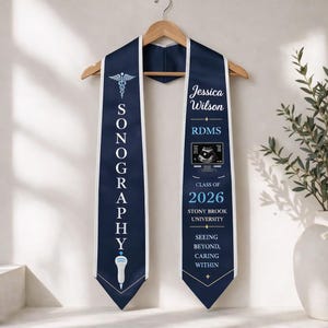 Può includere: Stola di laurea blu navy con finiture bianche, con la parola "SONOGRAPHY" in verticale. La stola include il nome "Jessica Wilson", "RDMS", e "Classe del 2026" con un'immagine ecografica e il logo della Stony Brook University.
