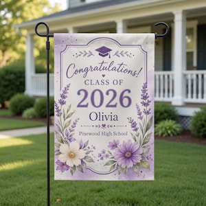 Puede incluir: Una bandera de jardín de graduación con un diseño floral en tonos morados y blancos. La bandera dice "¡Felicidades! Clase de 2026 Olivia" y "Pinewood High School". Un birrete está en la parte superior.