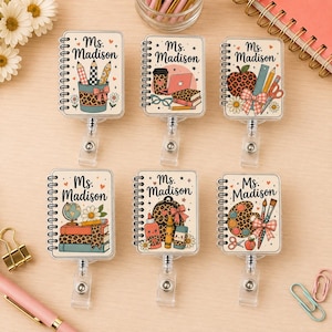 Peut inclure: Six enrouleurs de badge rectangulaires avec un motif de carnet à spirales et le texte Ms. Madison. Chaque enrouleur présente des illustrations scolaires différentes, notamment des crayons, un ordinateur, une pomme, un globe et une palette.