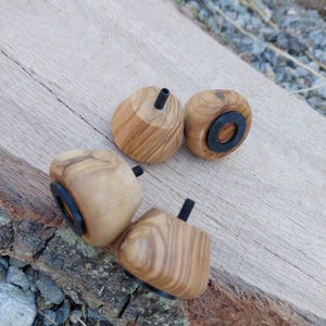 Könnte beinhalten: Vier Holzmöbelfüße mit hellbraunem Finish und schwarzer Hardware. Die Füße sind quadratisch mit abgerundeten Kanten und einem Gewindebolzen zur Befestigung. Die Holzmaserung ist sichtbar.