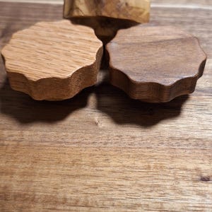 Op de afbeelding: Drie houten knoppen met een gegolfde rand. De knoppen zijn gemaakt van verschillende soorten hout, waaronder eikenhout en walnoot.