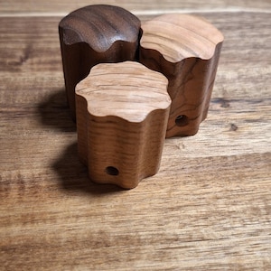 Könnte beinhalten: Drei Holzgriffe, einer dunkelbraun und zwei hellbraun, mit einem Sternmuster. Die Griffe liegen auf einer Holzoberfläche.