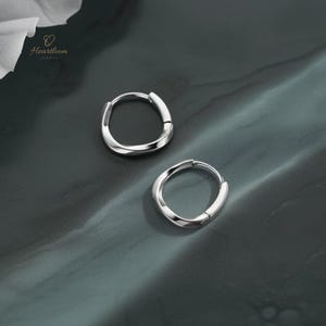 Può includere: Una tazza di ceramica bianca con manico nero e la scritta "But First, Coffee" in grassetto nero. La tazza è posta su uno sfondo sfocato, che suggerisce un'atmosfera accogliente.