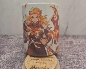 Op de afbeelding: Een witte keramische mok met een gedetailleerde illustratie van een anime-personage met vurig haar en een zwaard. De mok staat op een houten onderzetter met de naam "Mavuika" en inspirerende tekst. De mok heeft een zeshoekige vorm.