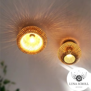 Puede incluir: Dos luminarias de techo redondas de bambú tejido con bombillas de luz blanca cálida. Las luces cuelgan de un techo blanco.