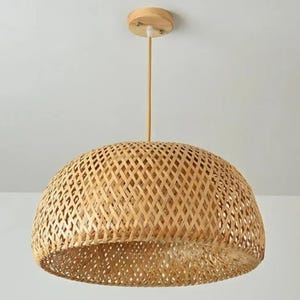 May include: A natural woven bamboo pendant light fixture with a dome-shaped shade. The light fixture has a simple design with a wooden ceiling mount.