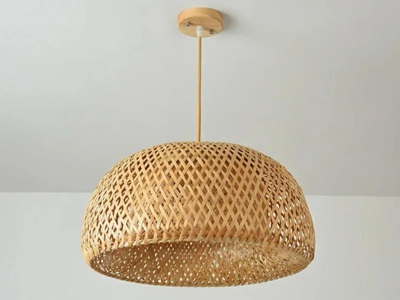 May include: A natural woven bamboo pendant light fixture with a dome-shaped shade. The light fixture has a simple design with a wooden ceiling mount.