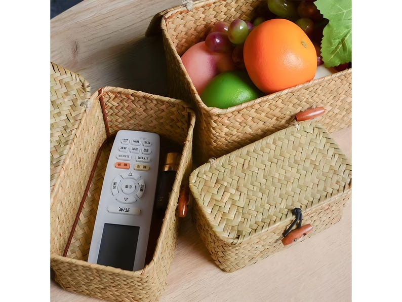 Puede incluir: Cestas de almacenamiento de hierba marina tejida en varios tama&ntilde;os. Una cesta contiene un mando a distancia y una botella peque&ntilde;a. Otra cesta contiene una naranja, uvas y una lima verde. Las cestas tienen cierres de palanca de madera.