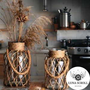 May include: Two clear glass jars with rope netting and handles. The jars are filled with dried plants and grasses. The jars have a rustic, bohemian style and are suitable for home decor. The jars are on a kitchen counter.