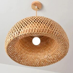 May include: A natural woven bamboo pendant light fixture with a round, dome-shaped shade. The light fixture has a natural wood finish and a white light bulb.
