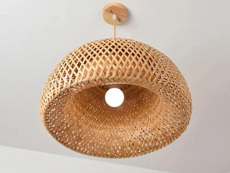 May include: A natural woven bamboo pendant light fixture with a round, dome-shaped shade. The light fixture has a natural wood finish and a white light bulb.
