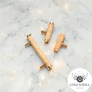 May include: Three cabinet pulls with a natural woven texture and gold-toned hardware. The pulls are cylindrical with a horizontal handle. The hardware is a T-shape. The cabinet pulls are in different sizes.