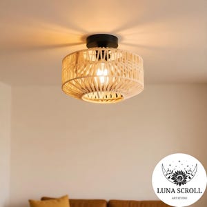 May include: A woven, beige ceiling light fixture with a black base. The light is round and has a natural, textured appearance. The fixture is suspended from the ceiling and illuminates the room with a warm glow.