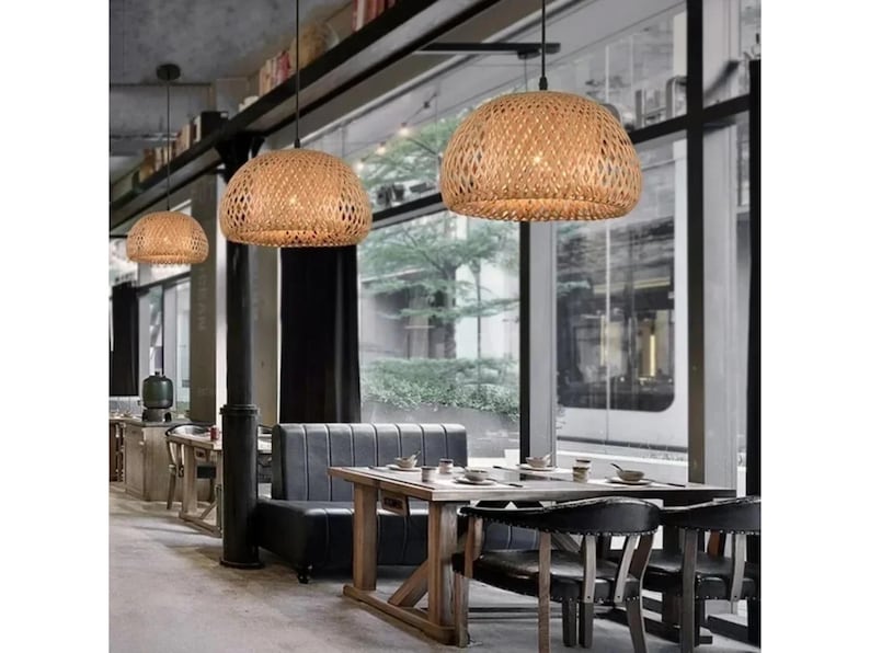 May include: A restaurant interior with a wooden table and chairs, a gray couch, and three woven pendant lights hanging from the ceiling.
