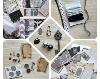 May include: A collection of craft supplies in shades of black, white, and gray, including fabric swatches, ribbons, beads, a decorative key, and small cards. The items are arranged on a light wood surface, creating a visually appealing assortment for crafting projects.