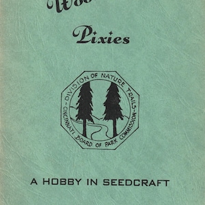 May include: A vintage teal-colored booklet titled "Woodland Pixies." The cover features the text "Woodland" in a script font, "Pixies" in a serif font, and a circular emblem with two trees. The text "A Hobby in Seedcraft" is also present.