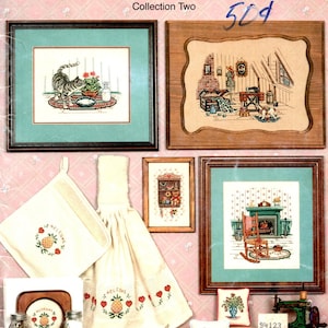 May include: A collection of cross-stitch patterns titled "Times Remembered" by Canterbury Designs. The image showcases framed cross-stitch samplers, including a cat, a cozy room, and kitchen accessories with pineapple and heart motifs. Book 61.