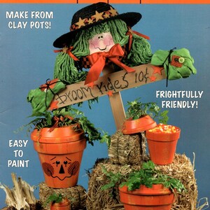 May include: A McCall's pattern cover featuring a Halloween-themed craft project. The image showcases painted clay pots decorated as scarecrows and a sign that reads "Broom Rides 10¢". The text "Easy to Paint" is also visible.