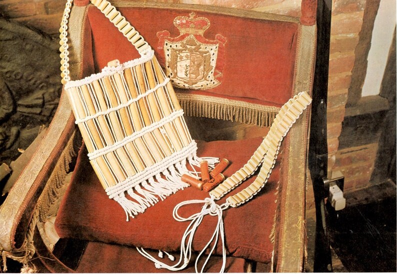 May include: A handcrafted bag and belt set made from light-coloured wooden beads and white string, with a fringed base. The bag is rectangular and the belt is long. The set is displayed on a red velvet chair.