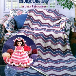 May include: A crochet pattern book titled "Learn to Crochet in Just One Day" by Jean Leinhauser. The cover features a handmade blanket with a wavy pattern in white, burgundy, and blue. A doll in a pink and white dress is also shown.