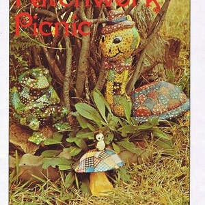 May include: A whimsical scene featuring patchwork creatures in a natural setting. The image includes a frog, a caterpillar, a turtle, and a mushroom, all adorned with colorful fabric patches. The text "Patchwork Picnic" is visible at the top.