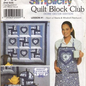 May include: Simplicity Quilt Block Club Home Decor Edition pattern. The image shows a quilt with heart and windmill patchwork designs. Also shown is a matching apron and other home decor items. The pattern is size "one size".
