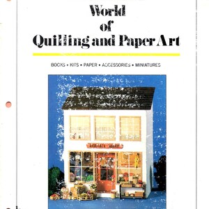 May include: A page from "World of Quilling and Paper Art" by Barbara Maddox. The image features a miniature model of a shop with the name "Quill Art, inc." at the bottom. The shop has a red door and is filled with miniature items.