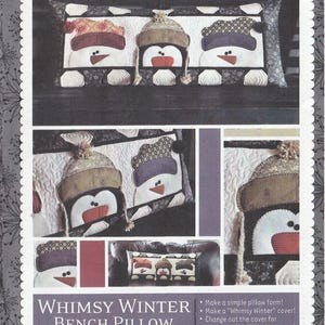 May include: A Kimberbell Whimsy Winter Bench Pillow pattern kit, KD164, featuring three appliqued snowmen wearing patterned hats. The rectangular pillow cover displays snowmen with orange noses and black eyes. Includes instructions for a 16 x 38 inch pillow.