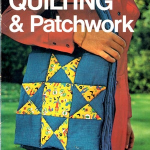 May include: A book cover titled Quilting & Patchwork featuring a blue quilted bag with a yellow star-shaped patch pattern decorated with small illustrations of figures, roosters, and apples, worn over a red long-sleeved garment.