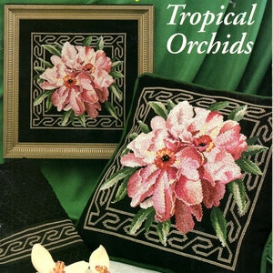 May include: A cross-stitch pattern featuring a floral design of pink and red orchids, framed and on a pillow. The text "Tropical Orchids" is displayed. The pattern is by Marie Barber.
