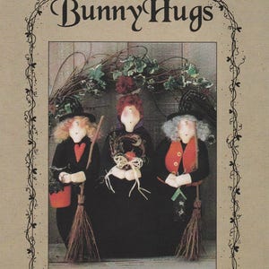 May include: A decorative print featuring three standing witch dolls, each with a unique hat, broom, and outfit. The text "Bunny Hugs" arches above the dolls, with "Hocus Pocus" and "16 1/2" standing witches" below. The image has a rustic, handcrafted aesthetic.