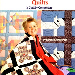 May include: A book cover titled "Patchwork Animal Quilts" featuring a smiling child wrapped in a patchwork quilt. The quilt has a teddy bear design. The cover also displays the text "8 Cuddly Comforters" and the author's name.