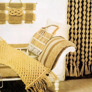 May include: A selection of macrame home decor items in natural tones. The image shows a wall hanging with a knot design, a fringed runner, a tote bag, and a decorative curtain. The items are displayed on a white bench and against a white wall.