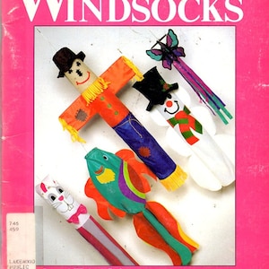 May include: A book cover titled "Let's Make Seasonal Windsocks" with a pink background. The cover features four seasonal windsock designs: a scarecrow, a snowman, a butterfly, and a fish. The book includes patterns and instructions by Valerie J. Lund.
