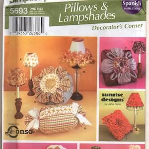 May include: Simplicity pattern 5693 for home decorating, featuring pillows and lampshades. The image showcases various designs, including floral and patterned pillows, and lampshades with decorative elements. Includes Spanish instructions.