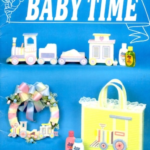 May include: A craft book cover titled "BABY TIME" features a blue background with a train, wreath, and tote bag designs. The cover includes the text "Designed By Cheryl Hofe" and "NEEDLEWORK FOR PLASTIC CANVAS".