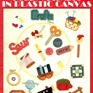 May include: A collection of 16 colorful plastic canvas magnets featuring various craft-themed designs, including a sewing machine, a paintbrush, a spool of thread, a ruler, a basket, a heart, a strawberry, and the word "Crafts".