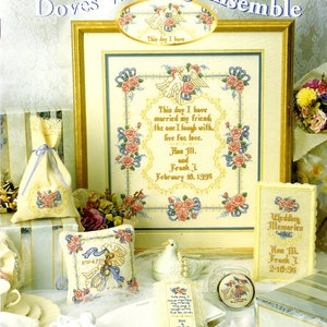 May include: A collection of cross-stitch wedding-themed items. The centerpiece is a framed piece with doves, roses, and the text "This day I have married my friend." Other items include a pillow, a bookmark, and a small box, all with similar designs.