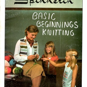 May include: A vintage book cover titled "Spinnerin" with the text "Basic Beginnings Knitting." The image shows a woman teaching two young girls how to knit. Colorful yarn balls are in a basket and on a table. The cover has a retro aesthetic.