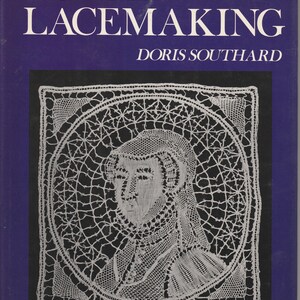 May include: A hardcover book titled Bobbin Lacemaking by Doris Southard with a deep blue cover. The front features a white, intricate lace portrait of a person wearing a head covering, set within a circular frame on a black square background.