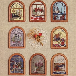 May include: A book cover titled "Rooms With A View" featuring nine framed cross-stitch designs depicting various scenes. The designs include landscapes, buildings, and a cat. The cover also includes the text "BOOK #8" and "BETTE ASHLEY DESIGNS".