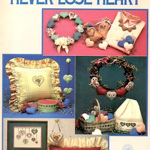 May include: A leaflet titled "Never Lose Heart" featuring various heart-themed crafts. The image showcases a heart-shaped wreath, decorative pillows, a framed cross-stitch, and other heart-shaped ornaments in various colors and patterns.