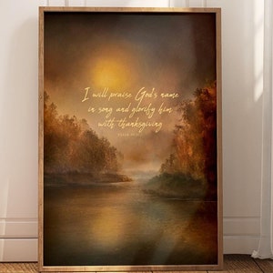 May include: Framed art print featuring a serene landscape with a river and trees, bathed in warm, golden light. The artwork includes the text "I will praise God's name in song and glorify him with thanksgiving" from Psalm 69:30.