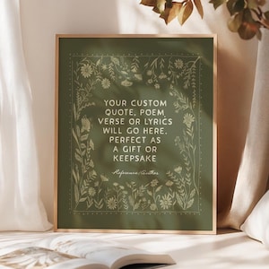 Puede incluir: Una impresión enmarcada con un fondo verde y un borde floral dorado. El texto dice: "TU CITA, POEMA, VERSO O LETRAS PERSONALIZADAS IRÁN AQUÍ. PERFECTO COMO REGALO O RECUERDO". Un libro abierto descansa frente a la impresión.