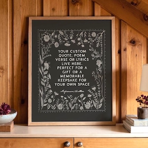 May include: A framed print with a black background and white floral border. The text reads: "YOUR CUSTOM QUOTE, POEM, VERSE OR LYRICS LIVE HERE. PERFECT FOR A GIFT OR A MEMORABLE KEEPSAKE FOR YOUR OWN SPACE."