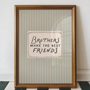 Może przedstawiać: Oprawiony wydruk z napisem "Brothers make the best friends" w ozdobnym znaku. Rama jest brązowa, a tło ma pionowe paski w kolorze jasnoniebieskim i białym. Wydruk jest wyświetlany na czarno-białej podłodze w paski.