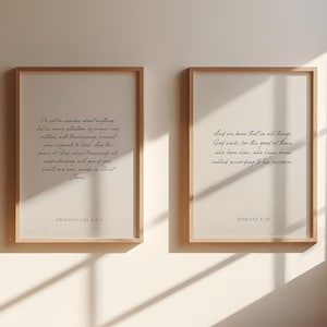 May include: Two framed prints with white backgrounds and black text. The left print features the text "Do not be anxious about anything, but in every situation, by prayer and petition, with thanksgiving, present your requests to God. And the peace of God, which transcends all understanding, will guard your hearts and your minds in Christ Jesus." with the text "Philippians 4:6-7" below. The right print features the text "And we know that in all things God works for the good of those who love him, who have been called according to his purpose." with the text "Romans 8:28" below.
