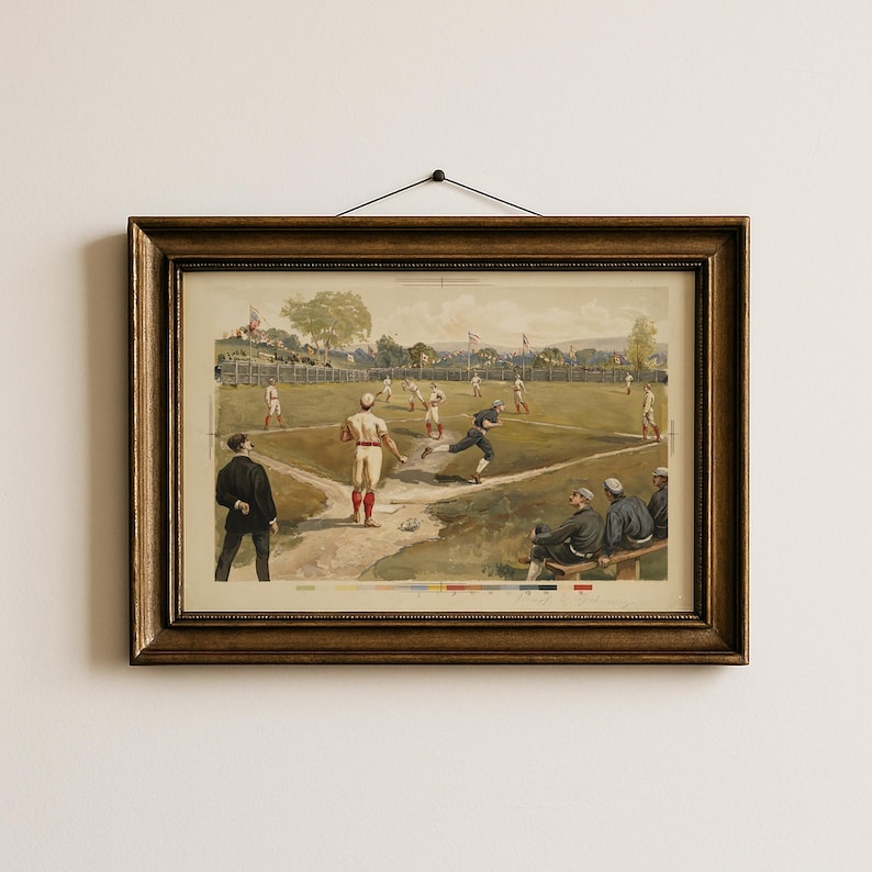 May include: A framed vintage baseball print. The artwork depicts a baseball game in progress, with players in period uniforms on a green field. The frame is a dark, ornate wood. The print has a sepia tone.